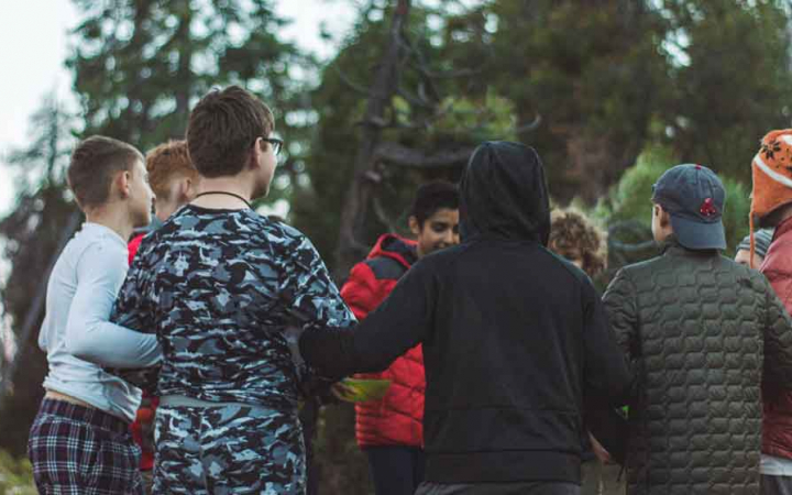 a group of young people stand in a circle with their arms linked
